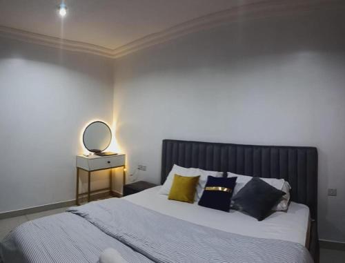 a bedroom with a bed with pillows and a mirror at Delight 1 Bedroom Apartment - Off Awolowo Road Ikeja in Ikeja