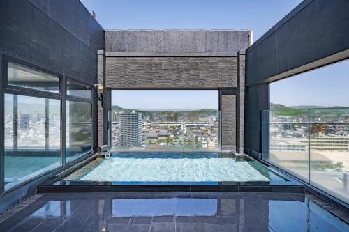 an indoor swimming pool in a building with windows at Candeo Hotels Fukuyama in Fukuyama