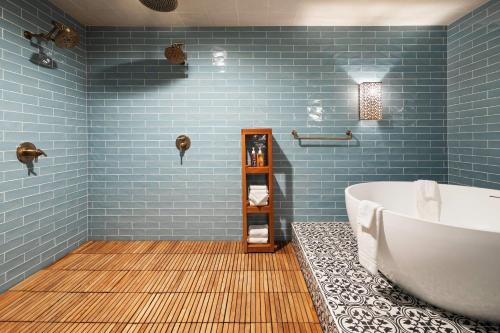 a bathroom with blue tiles and a tub at The Highlander Hotel, Ascend Hotel Collection in Iowa City