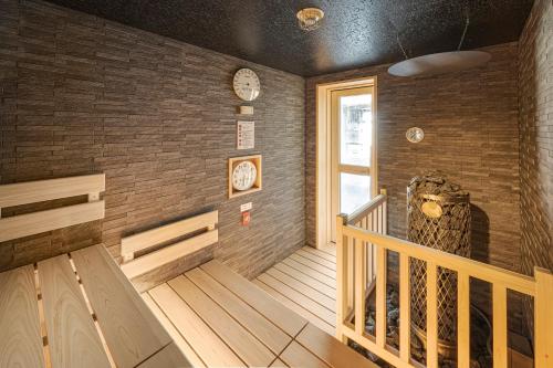 a room with a wooden staircase with clocks on the wall at Candeo Hotels Fukuyama in Fukuyama