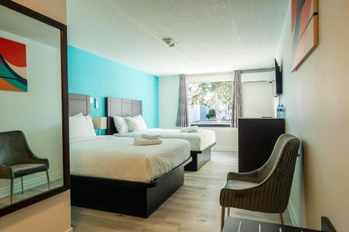 a hotel room with two beds and a mirror at Howard Johnson by Wyndham Brampton in Brampton