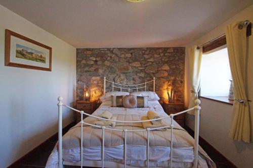 a bedroom with a bed with a stone wall at Beudy Lleuddad in Llangwnadl