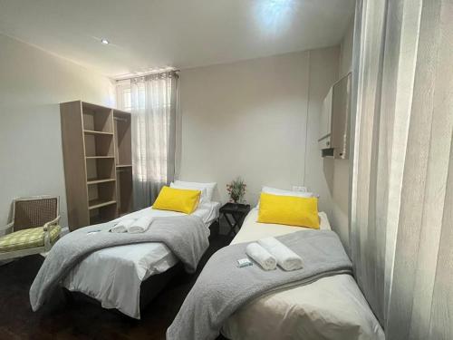 two beds in a room with yellow pillows at HEBA GUEST LODGE in Uitenhage