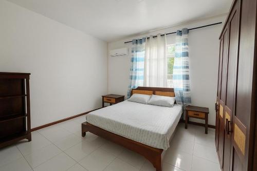 a white bedroom with a bed and a window at Perle rare Lodge in Diamond Island