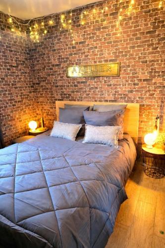 a bedroom with a brick wall and a large bed at L atelier des jeux in Beauvais
