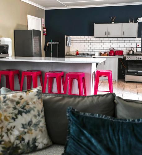 a living room with red stools in a kitchen at Summerville Place in Addo