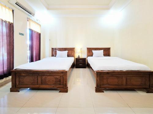 two beds in a room with two bedsitures at Hotel Syariah Milik Kita Borobudur Mitra RedDoorz in Borobudur