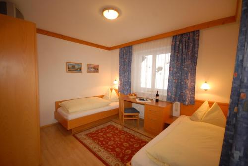a bedroom with two beds and a desk and a window at Jugendpension Müllauerhof in Saalbach Hinterglemm