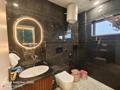 a bathroom with a sink and a toilet and a mirror at Hotel Akshansh Inn in Agra