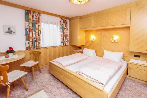 a bedroom with a large bed and a table at Gästehaus Rosi in Fieberbrunn