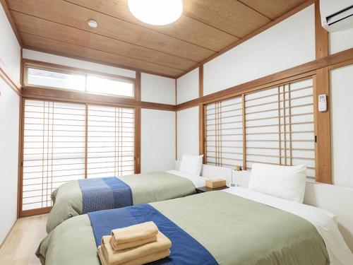 two beds in a room with windows at わのおうち善 in Nitanzawa