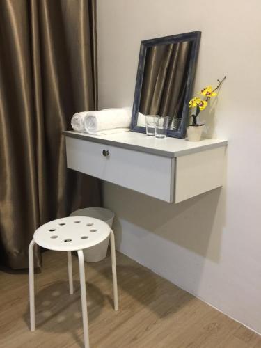a white dresser with a mirror and a stool at The b'Hotel in Kajang