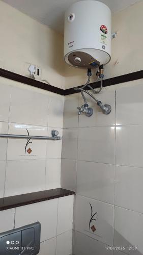 a light on the wall of a bathroom with white tiles at Hotel Raaj Inn Service Apartment in Chennai