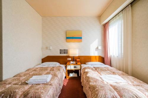 a hotel room with two beds and a window at 南部ホテル in Kitakami