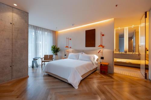 a bedroom with a large white bed and a desk at The Cut Hotel in Medellín