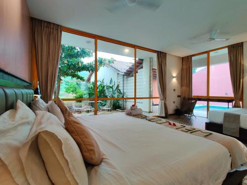 a large bed in a room with a large window at Touchwood Bliss Nature Retreat - Igatpuri in Igatpuri