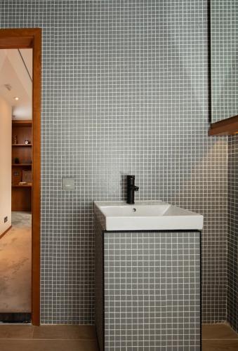 a bathroom with a sink and a tiled wall at Oootopia Tai Kok Tsui in Hong Kong