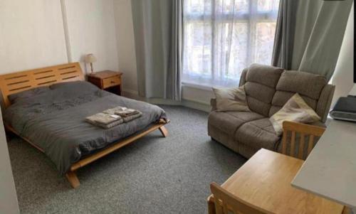 a bedroom with a bed and a couch and a table at Self contained Studio apartments in Eastbourne