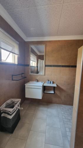 a bathroom with a white sink and a mirror at Maggie's Farm Stay in Khanzi