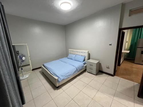 a bedroom with a bed with blue sheets and a fan at Spacious one bedroom Bangalow -8E3 in Kampala