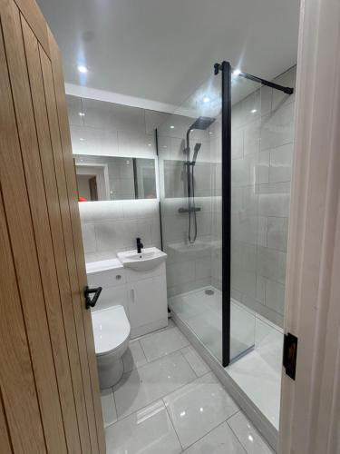 a white bathroom with a shower and a toilet at Olivers retreat in Braintree