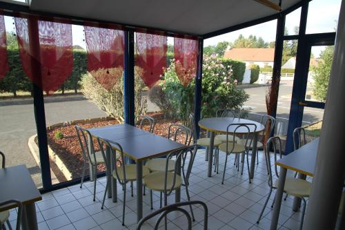 a patio with tables and chairs in a restaurant at Europe Hôtel in Varennes Vauzelles