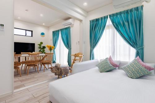 a living room with a white bed and blue curtains at Katan A in Yamada