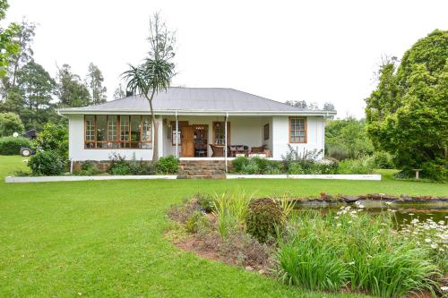 a white house with a pond in the yard at Burnside Lodge in Balgowan