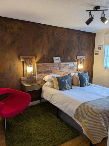 a bedroom with a large bed and a red chair at Boutique Coastal appt nr Edinburgh in Saint Davids