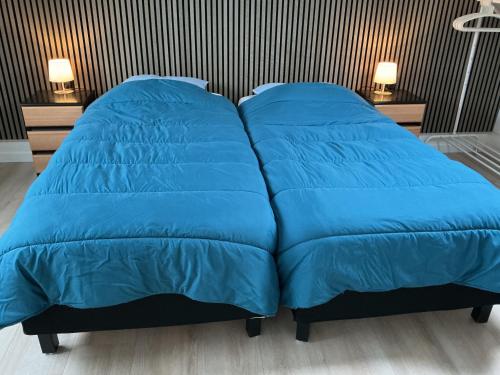 a large blue bed with two pillows on it at Zomerhuis Zwart in Egmond aan Zee