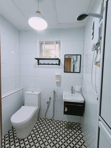 a white bathroom with a toilet and a sink at Desa Ibol Cottage and River - Max 10Pax in Kampong Sumpitan
