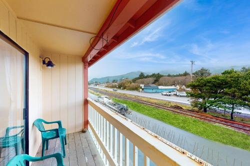 a balcony with two chairs and a view of a train track at Sea Treasures Inn #211 in Rockaway Beach