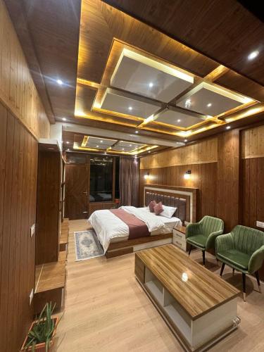 a bedroom with a bed and two green chairs at Willow Winds Home Stay in Theog