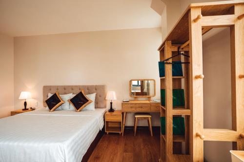 a bedroom with a bed and a desk with a mirror at EcoHouse Boutique Hotel Huế in Hue