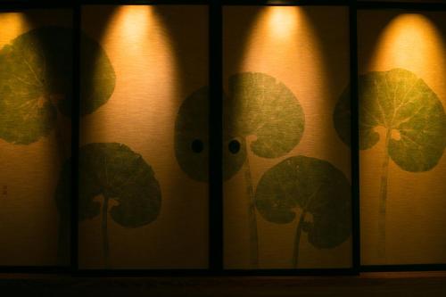 a curtain with green leaves on it with lights at Fukiya Ryokan in Yugawara