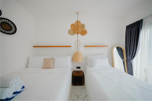 two beds in a room with white sheets at Ayodhya Villa Utari - North Wings in Yogyakarta