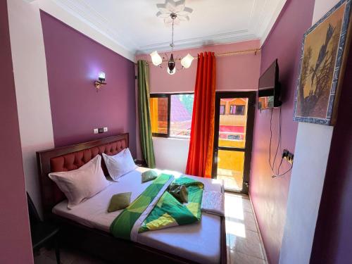 a bedroom with a bed with purple walls and a window at NGK Hôtel Apartment in Bafoussam