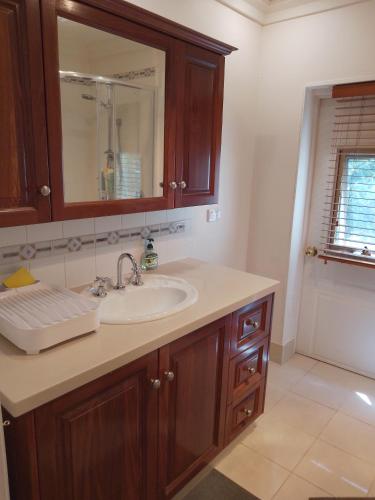 a bathroom with a sink and a mirror at Elegant Holiday Studio in Werribee
