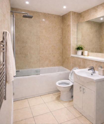 a bathroom with a tub and a toilet and a sink at Astral Court Premium Accomodation in Ruislip