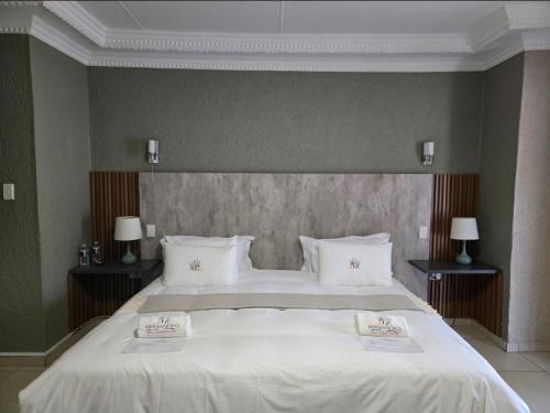 a bedroom with a large white bed with two lamps at Mminanoko Eco Guesthouse in Mamphokgo