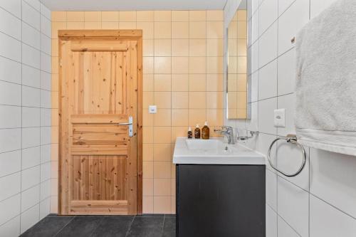 a bathroom with a sink and a wooden door at Panoramic Alpine Garden Retreat in Vissoie