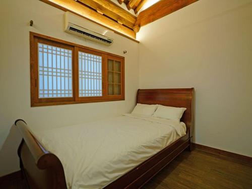 a bedroom with a bed in a room with a window at Jeonju Hanok Agbae in Jeonju
