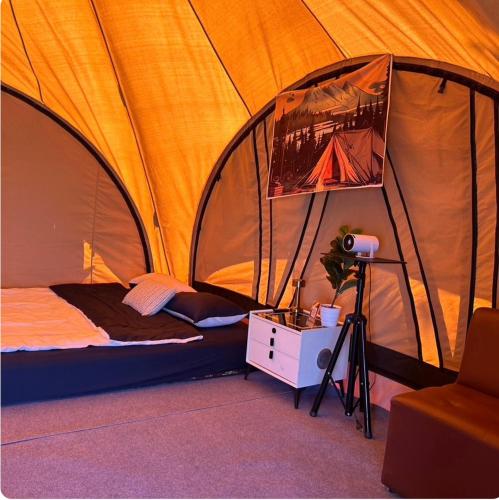 a tent with a bed and a lamp in a room at Sireha Cafe Resort and Glamping in Ban Khok Chang