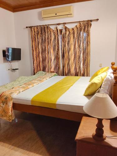 a bedroom with a large bed with curtains and a lamp at Mansion Du Lac in Kottayam