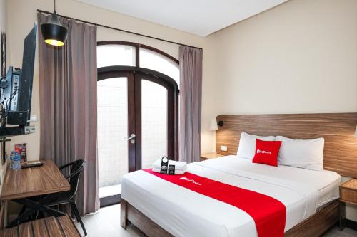 a bedroom with a bed and a desk and a window at RedDoorz @ Wiyung 2 in Kedurus