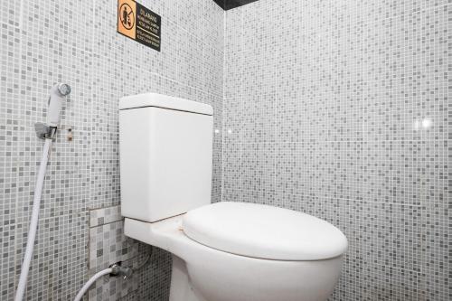 a bathroom with a white toilet in a tiled wall at RedDoorz @ Wiyung 2 in Kedurus