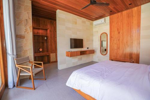 a bedroom with a bed and a chair and a tv at Villa Sucasas, Luxury Pool Villa Nusa Dua, Bali in Nusa Dua
