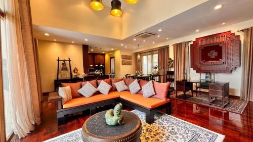 a living room with an orange couch and a table at Luxury Balinese Pool Villa in Na Jomtien