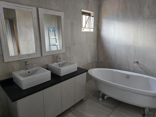 a bathroom with two sinks and a bath tub at Mminanoko Eco Guesthouse in Mamphokgo