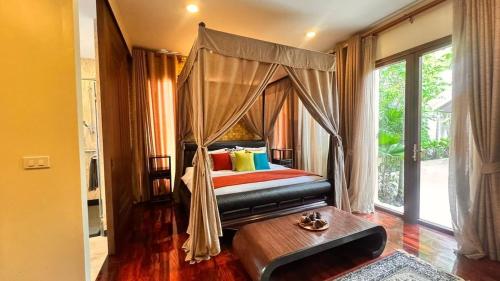 a bedroom with a canopy bed and a table at Luxury Balinese Pool Villa in Na Jomtien